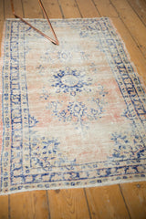 Distressed vintage Oushak rug texture with faded pale blush and navy floral patterns.