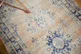 Decorative distressed texture of pale blush and navy blue patterns on a vintage Oushak runner.