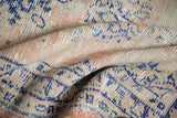 Distressed Oushak rug's soft, worn pile in pale blush, beige, and navy cobalt blue.
