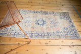 Distressed Oushak runner corner showcasing navy blue border, pale blush field, mostly even wear.