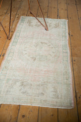 Secured end of the distressed Oushak runner, showing even wear with pale pink and seafoam colors.