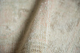 Distressed texture of vintage Oushak rug pile, featuring soft pale pink and ivory tones.