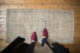 Corner of a vintage distressed Oushak rug runner, showing even wear and charcoal vine border.