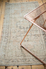 Distressed Oushak rug detail: worn pile with pale sand beige and charcoal vine border.