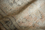Distressed Oushak rug texture with even wear, revealing pale sand and charcoal foundation.