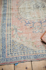 Decorative distressed texture with pale rose and cobalt blue motifs on a vintage Oushak.