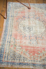 Detailed view of distressed Oushak rug's worn texture in dusty rose and cobalt blue.