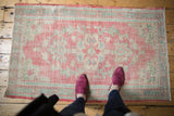 Distressed Turkish Oushak rug corner, pale raspberry, antique ivory, seafoam green, with visible wear.