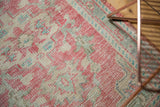 Distressed Oushak rug texture, pale raspberry, antique ivory, seafoam mint, with visible foundation.
