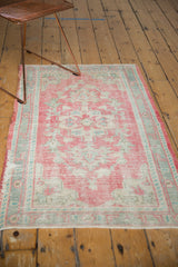 Distressed vintage Oushak rug with pale raspberry blush field and seafoam mint green border.