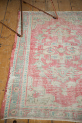 Distressed vintage Oushak rug with worn raspberry blush pile, foundation showing through, and mint green border.