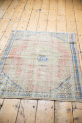 Distressed texture and foundation showing on a pale rose, ivory, and cobalt blue vintage Oushak.
