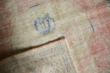 Folded distressed Oushak rug revealing worn knot heads, foundation, pale rose, and blue.