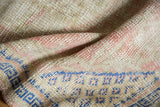 Distressed Oushak rug pile showing even wear, dusty rose, and cobalt blue geometric patterns.