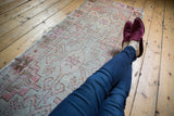 Distressed vintage Oushak runner showcasing faded pale blush geometric floral pattern with worn texture.