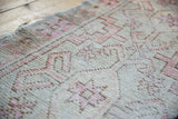 Distressed Oushak runner's worn pile texture, with faded blush pink, brown geometric motifs.