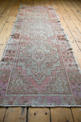 Distressed Oushak runner texture, showcasing pale blush, brown geometric patterns and even wear.