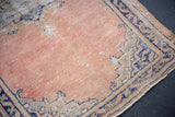 Distressed Oushak rug texture in dusty rose, with wear and blue meandering vine border.