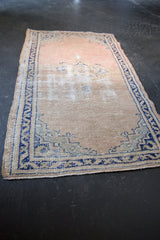 Textured distressed Oushak rug showing dusty rose field and cobalt blue geometric border.