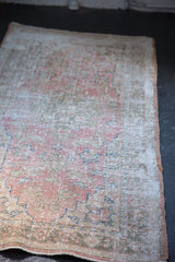 Distressed vintage Oushak rug detail, showing even wear to knot heads and faded floral motifs.