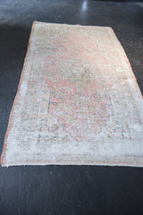 Even wear across the distressed Oushak rug's pile, revealing faded pink, beige, and blue motifs.