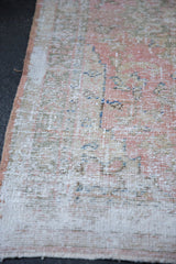 Distressed hand-knotted Turkish Oushak rug's texture with visible even wear and pale pink edge.