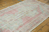 Distressed Oushak rug with soft rose, ivory, and pale sea-foam green texture.