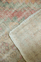 Distressed vintage Oushak rug pile revealing rose, green, and ivory tones with its woven foundation.