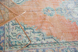 Distressed vintage Oushak rug with decorative texture, pale orange rust field, and mint green border.