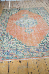 Oushak carpet end: distressed pile, pale rust field, navy blue palmette border, foundation showing.