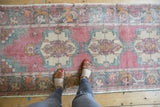Distressed vintage Oushak runner, faded rose, ivory, and sea-foam green patterns showing wear.