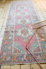 Distressed Oushak rug runner pile with faded rose, ivory, and sea-foam green geometric patterns showing wear.