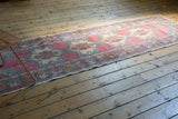 Faded cochineal red and rose distressed Oushak runner with visible foundation texture.