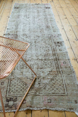 Distressed Oushak runner showing primitive floral border, seed motif, and secured fringe.