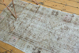 Distressed Oushak runner's worn texture revealing ivory, brown, and rose geometric patterns.