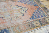 Distressed vintage Oushak runner border with rust apricot, cobalt blue, and green geometric pattern.