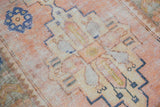 Distressed Oushak runner detail: worn pile, soft apricot, saffron, and cobalt hues.