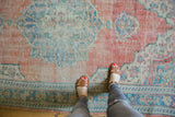 Decorative distressed Oushak rug showing worn pile in blush, aqua, and ivory.