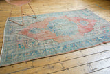 Distressed vintage Oushak carpet detail with even wear, softened brick red and aqua hues.