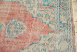 Distressed vintage Oushak rug, showing its worn pile texture and faded blush, ivory, aqua colors.