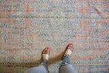 Vintage Distressed Oushak carpet with even wear across faded apricot, blue, and ivory floral vinery.