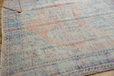 Distressed Oushak carpet corner with faded royal blue border and visible knot heads.