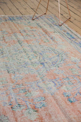 Distressed texture of a vintage Oushak carpet, featuring faded apricot and royal blue tones.