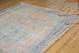 Textural view of distressed vintage Oushak rug, showing softened apricot, blue, and ivory hues.