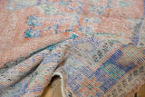 Distressed vintage Oushak carpet, detailed view of its worn, hand-knotted foundation in apricot, blue, ivory.