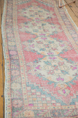 Distressed vintage Oushak runner, faded red, beige, and bubblegum pink Rococo motifs.