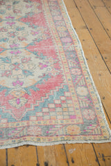 Distressed Vintage Oushak rug corner showing faded red rose, beige, and ocean green.