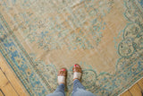 Distressed vintage Oushak rug showing worn pile with faded floral patterns in beige and blue.