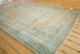 Distressed Oushak rug corner: mint green scalloped motifs, ocean blue vine border.
