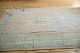 Worn pile texture of a distressed Oushak carpet with faded beige and mint green.